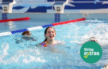 Image of a young girl splashing about and smiling in a swim lane at Stirling Leisure - Inglewood